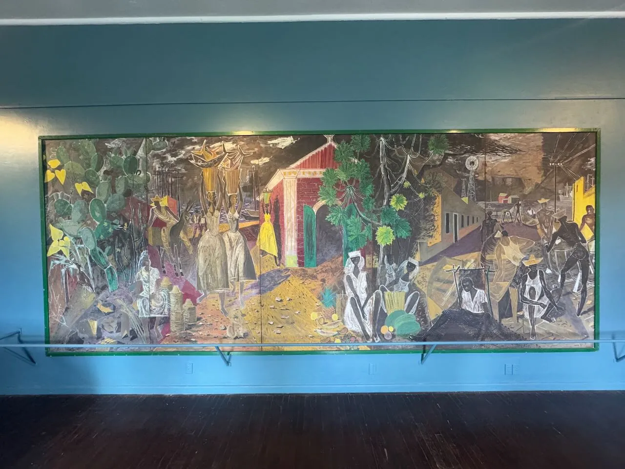 Large mural painting depicting Curacao island life with figures, cacti, and buildings